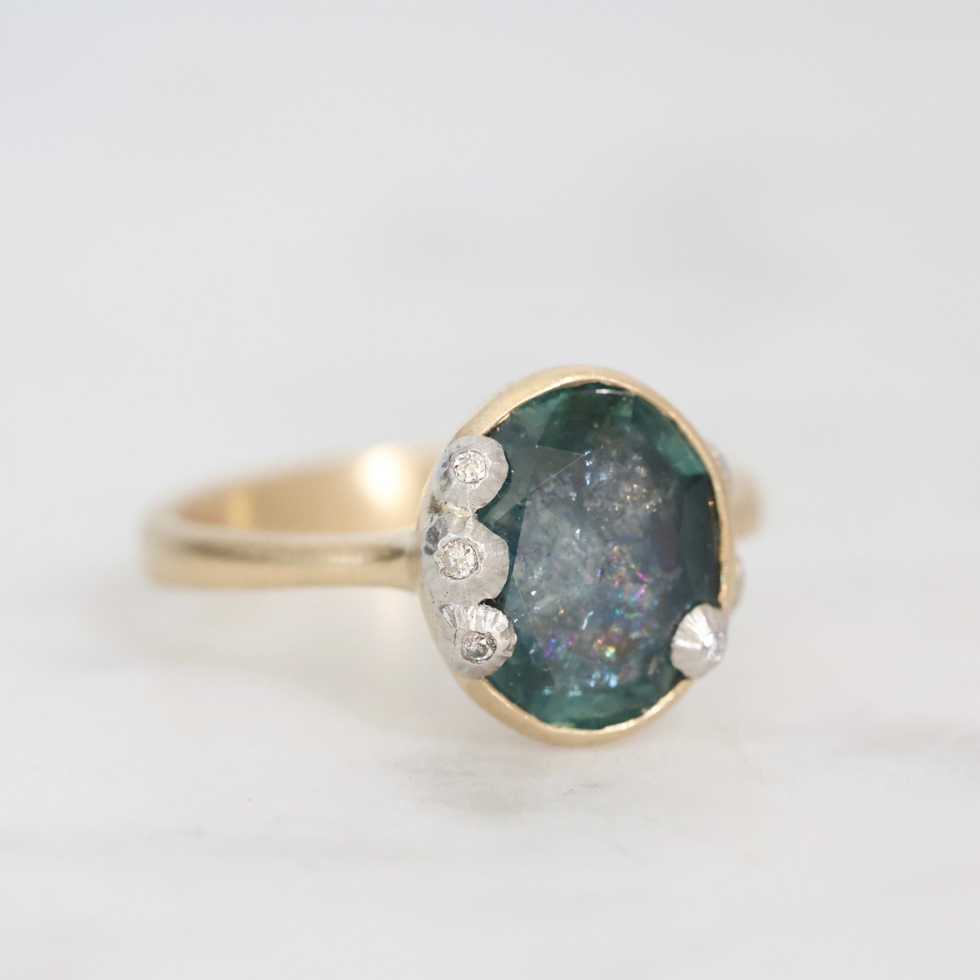 Ring with a green gemstone and gold band on a white background
