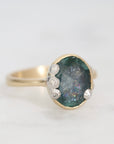 Ring with a green gemstone and gold band on a white background