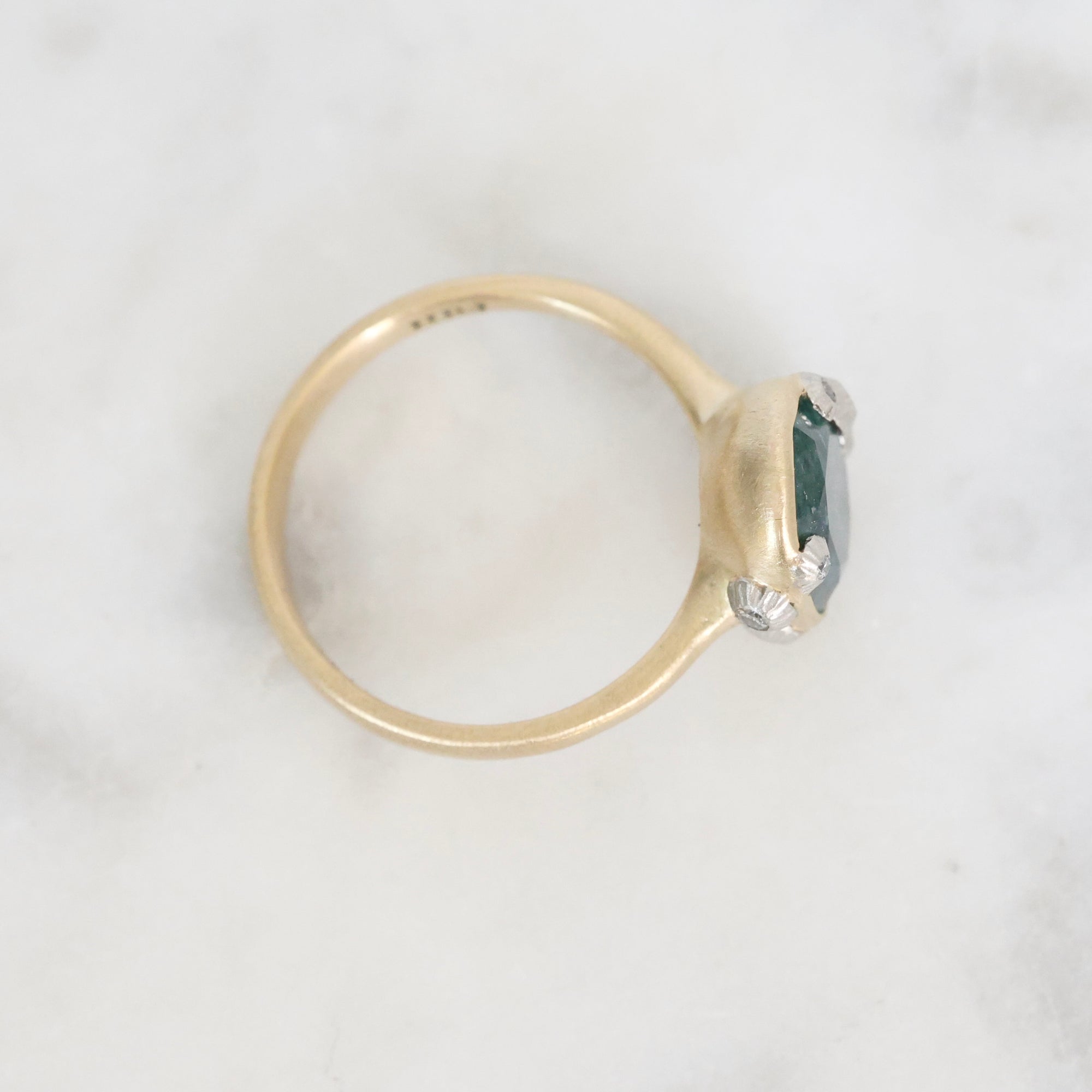 Gold ring with a green gemstone on a white background