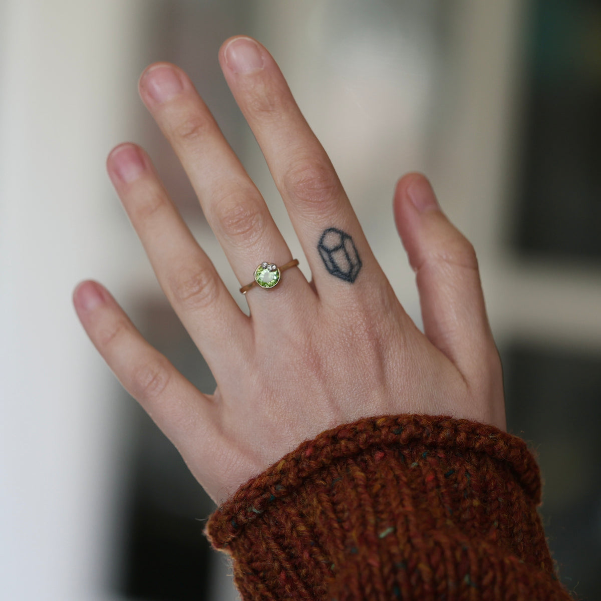 Hand wearing green stone ring.