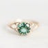 A gold ring featuring a round-cut green gemstone in a prong setting, photographed on a clean white background.