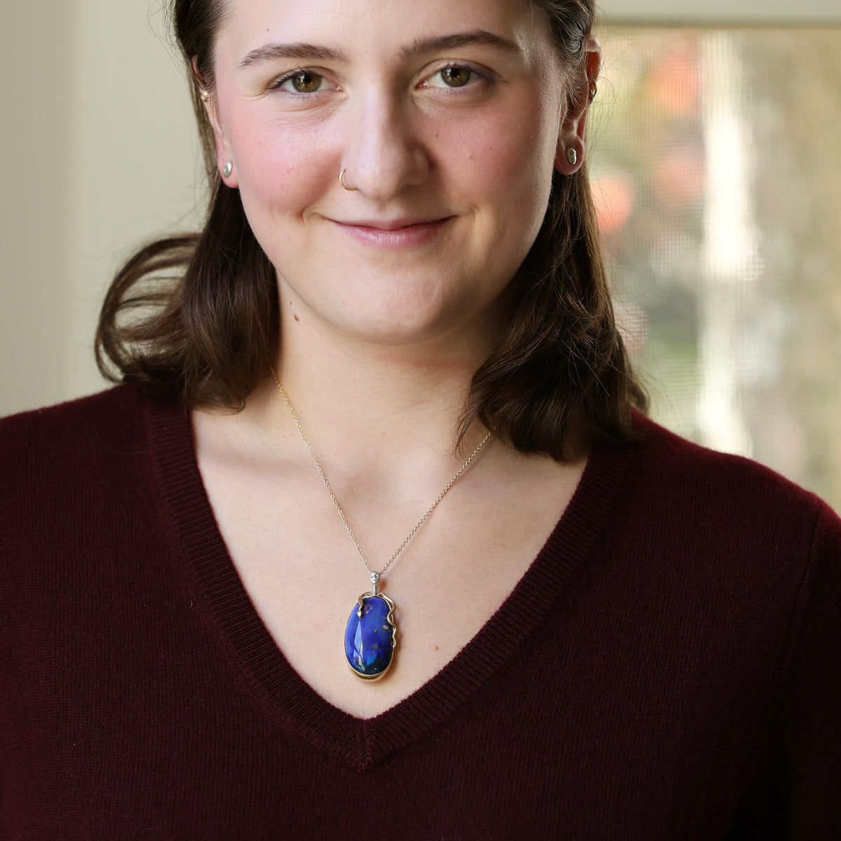 Woman wearing large pendant necklace. 