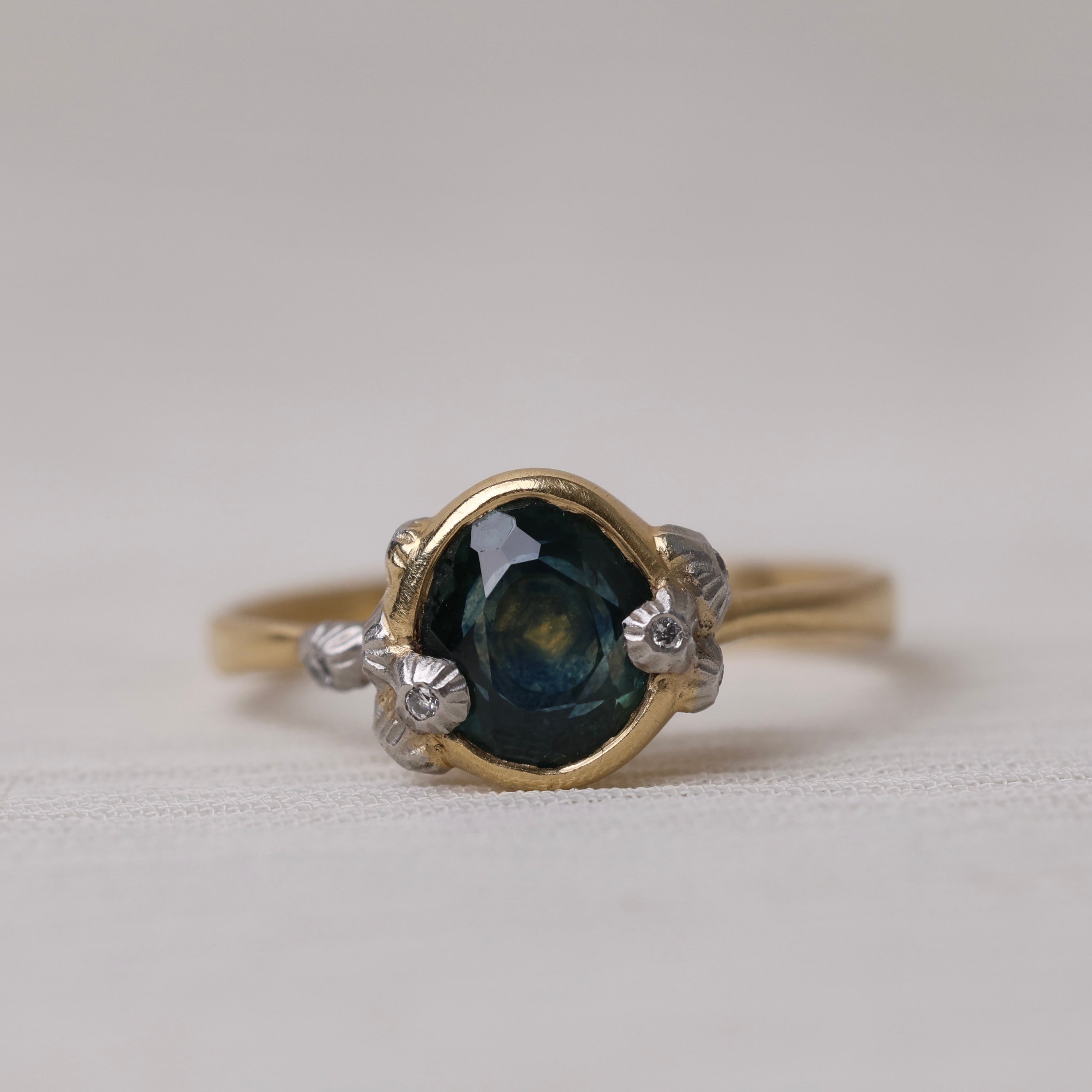 Gold ring with a green gemstone on a light gray background