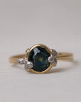 Gold ring with a green gemstone on a light gray background
