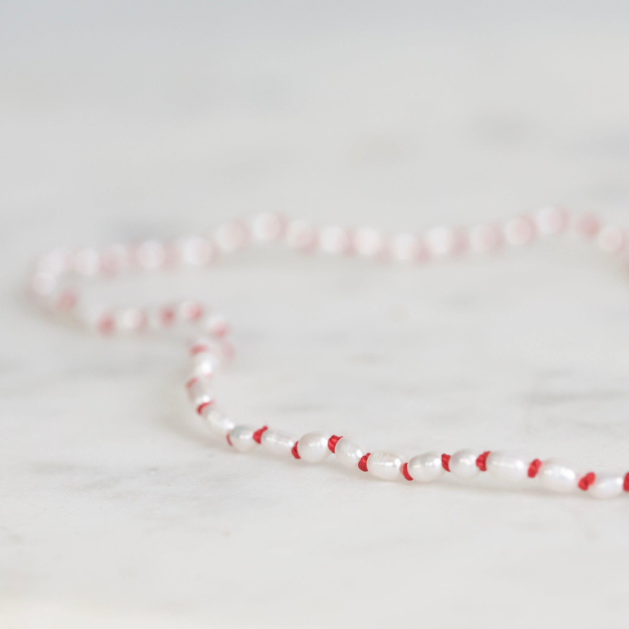 Necklace with red and white beads on a light gray background