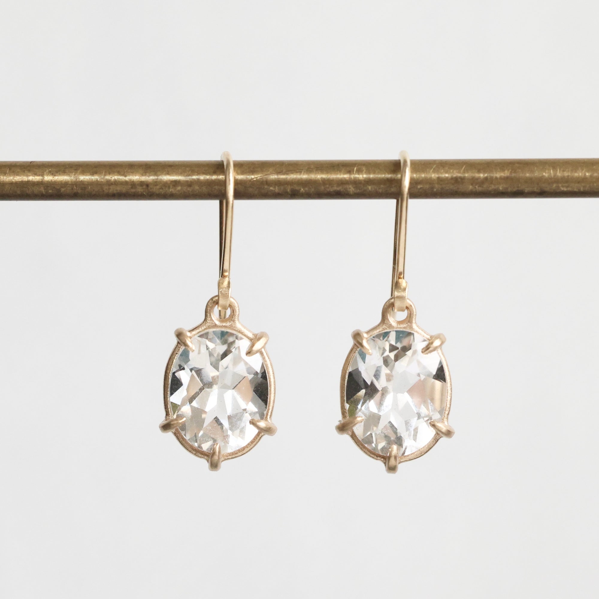 Gold earrings with clear gemstones on a white background