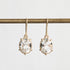 Gold earrings with clear gemstones on a white background