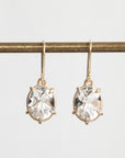 Gold earrings with clear gemstones on a white background