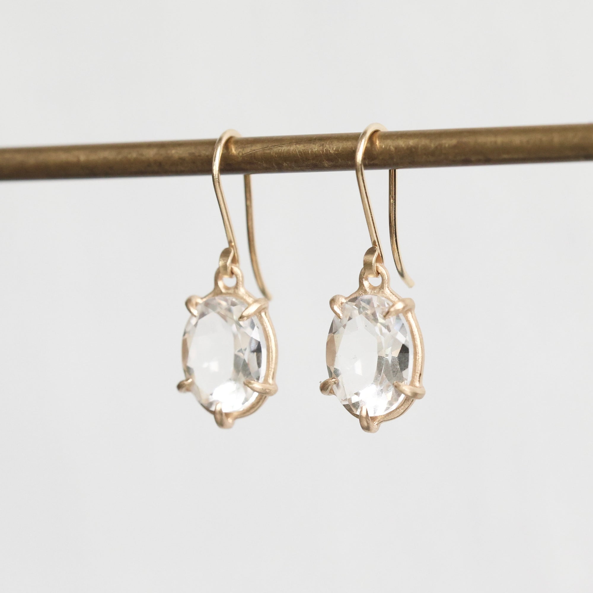 Gold earrings with clear gemstones on a light gray background