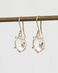 Gold earrings with clear gemstones on a light gray background