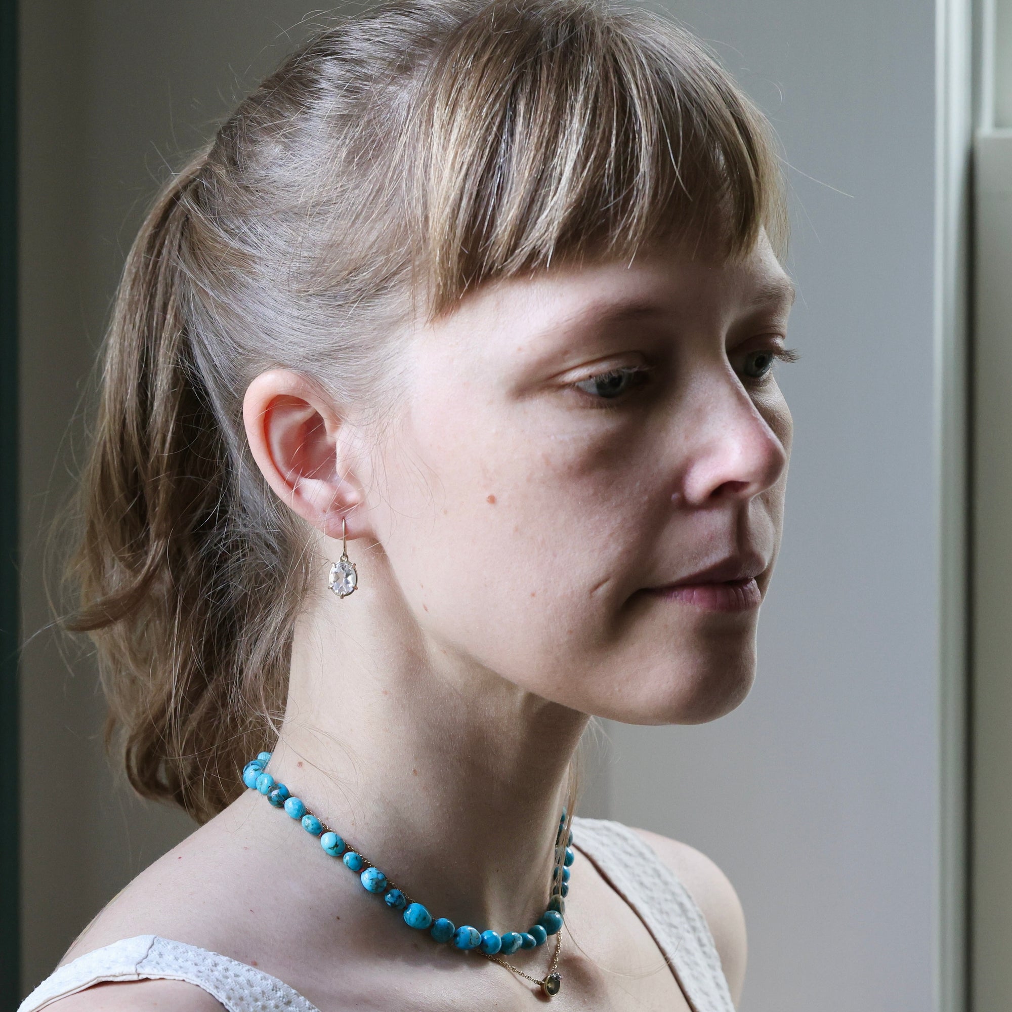 Woman wearing a blue beaded necklace with a neutral background
