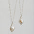 Two silver chain necklaces with oval white pearl pendants, each set with small gold and silver stones, shown against a light gray background.