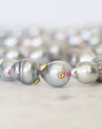 Close-up of a pearl necklace with gold and pink accents on a light background
