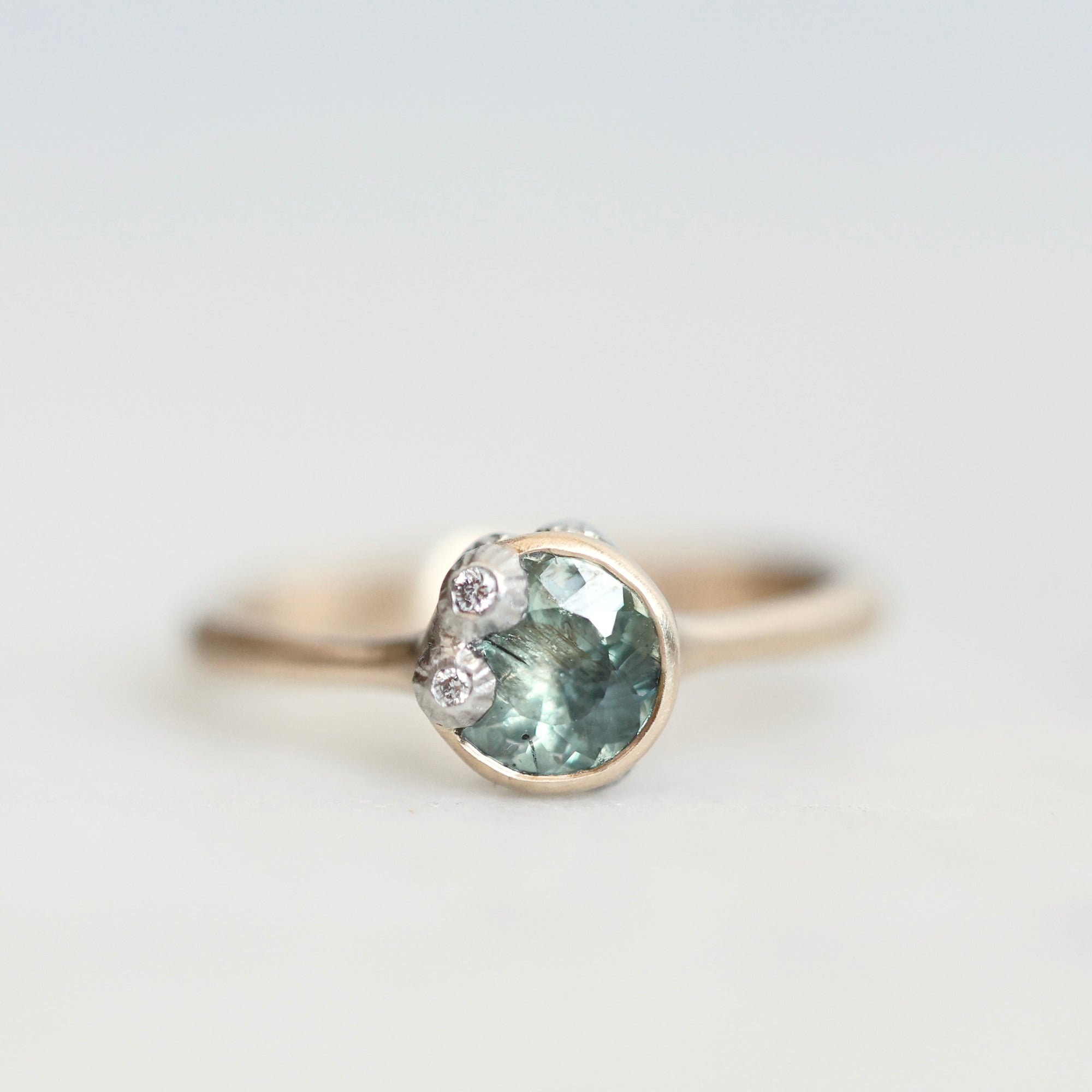Green sapphire ring in gold bezel setting with platinum barnacles set with tiny diamonds