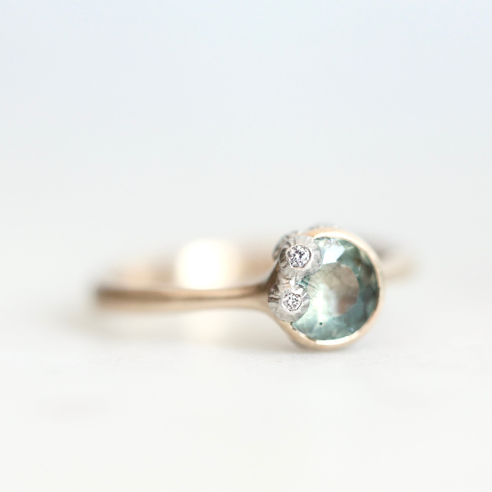Green sapphire ring set in gold bezel with platinum barnacles set with tiny diamonds 