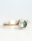 Green sapphire ring set in gold bezel with platinum barnacles set with tiny diamonds 