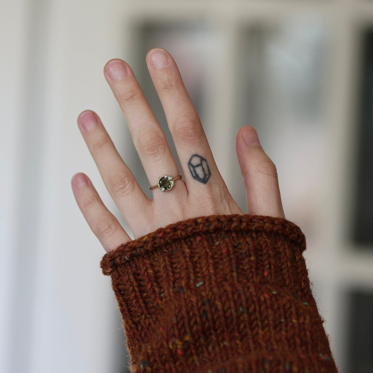 Hand wearing green gemstone ring