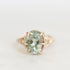 A round-cut light blue-green gemstone ring in a gold prong setting, photographed on a clean white background.