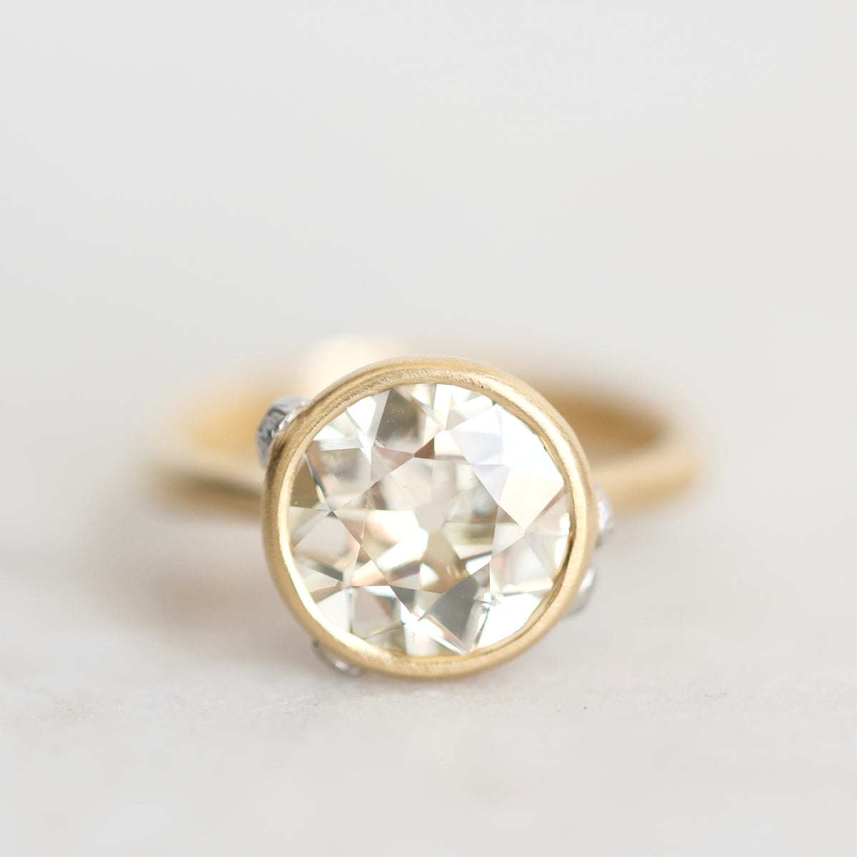 Diamond set in 18k yellow gold bezel against a white background