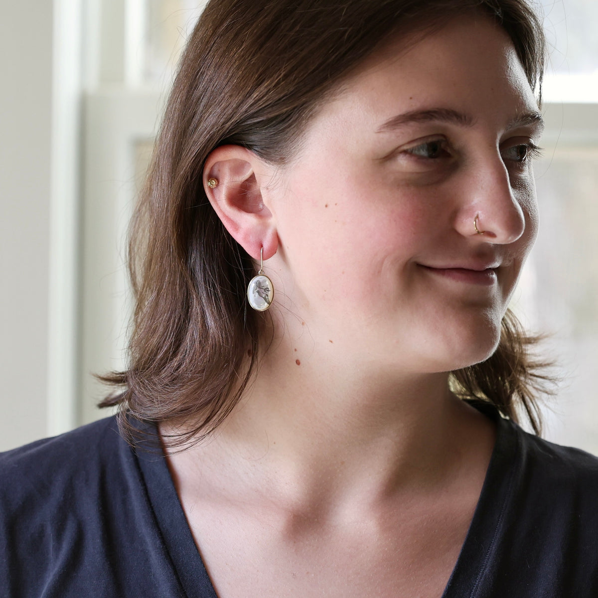 Woman wearing white drop earrings.