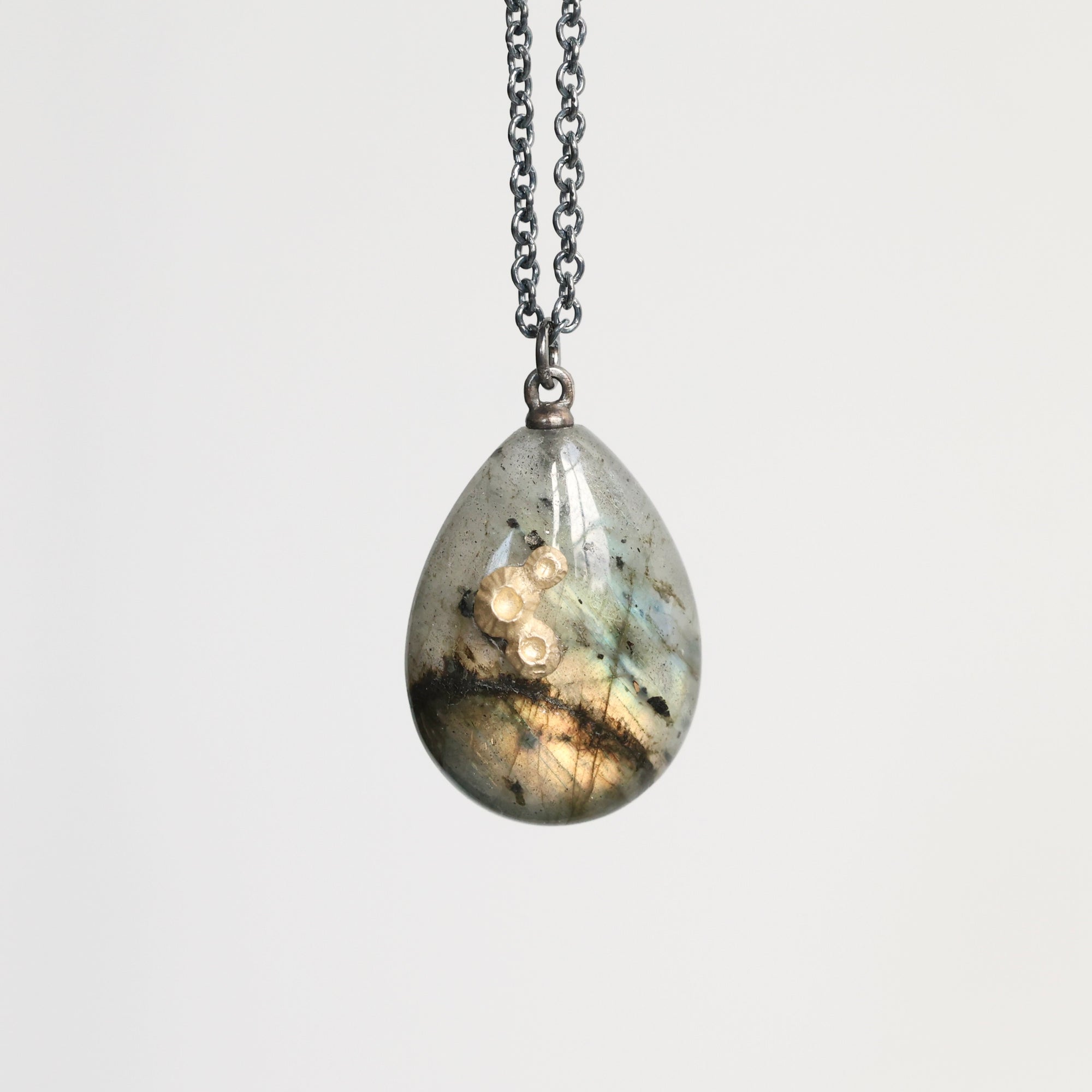 Teardrop-shaped pendant on a chain against a white background