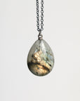 Teardrop-shaped pendant on a chain against a white background