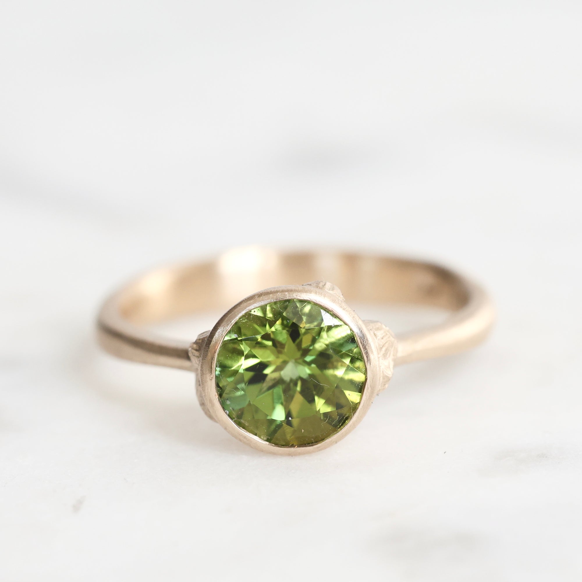 Gold ring with a green gemstone on a white background