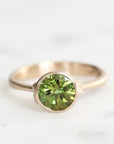 Gold ring with a green gemstone on a white background