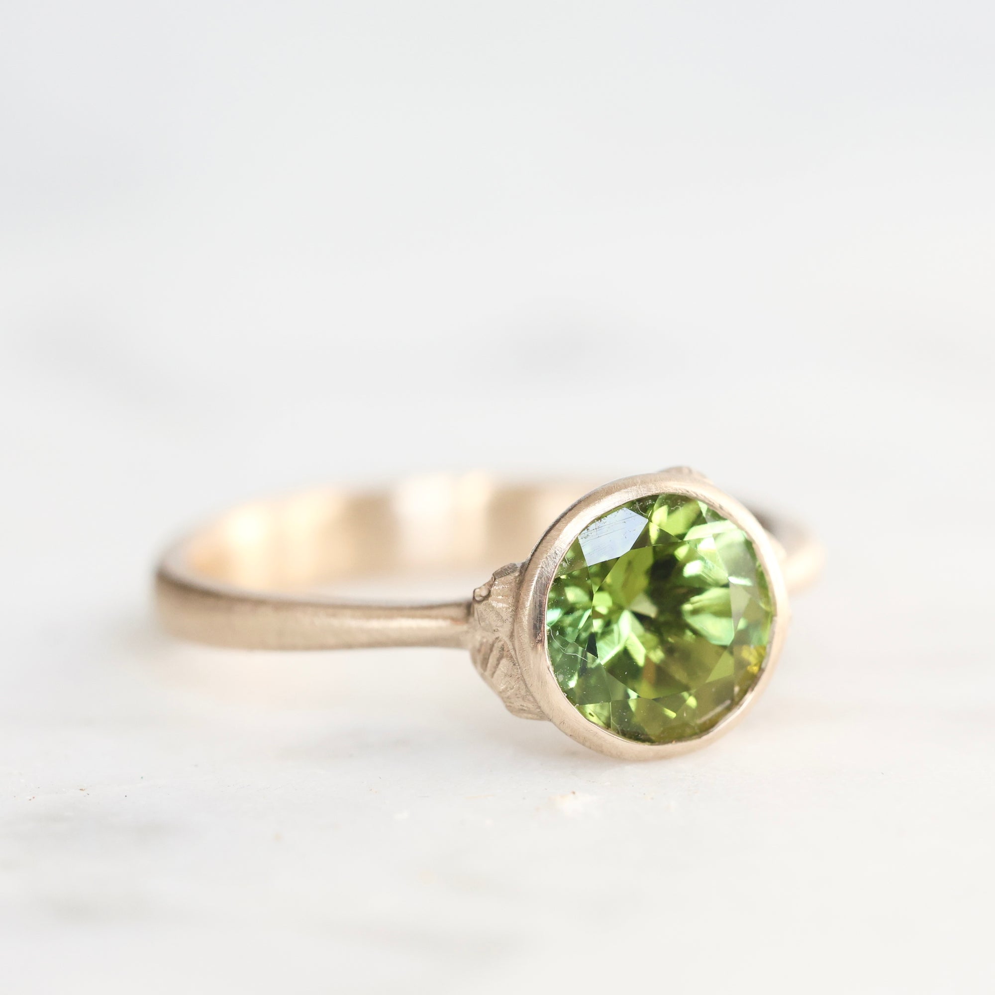 Gold ring with a green gemstone on a white background
