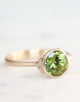 Gold ring with a green gemstone on a white background