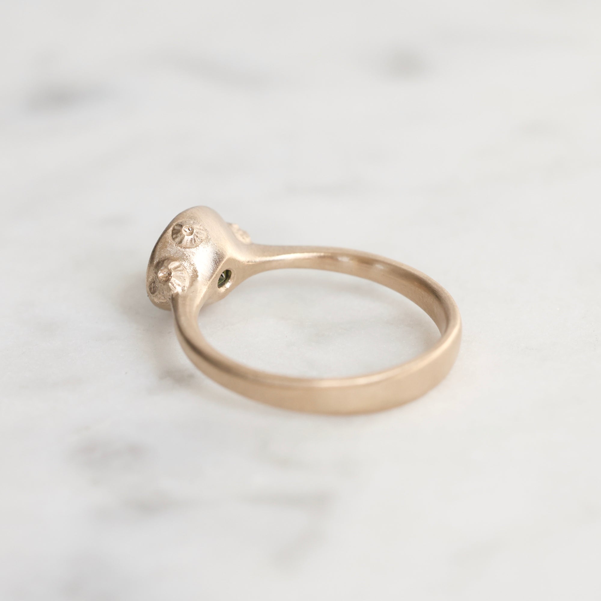 Gold ring with intricate design on a light gray background