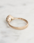 Gold ring with intricate design on a light gray background