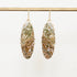 Pair of earrings with marbled green and brown stones on a white background