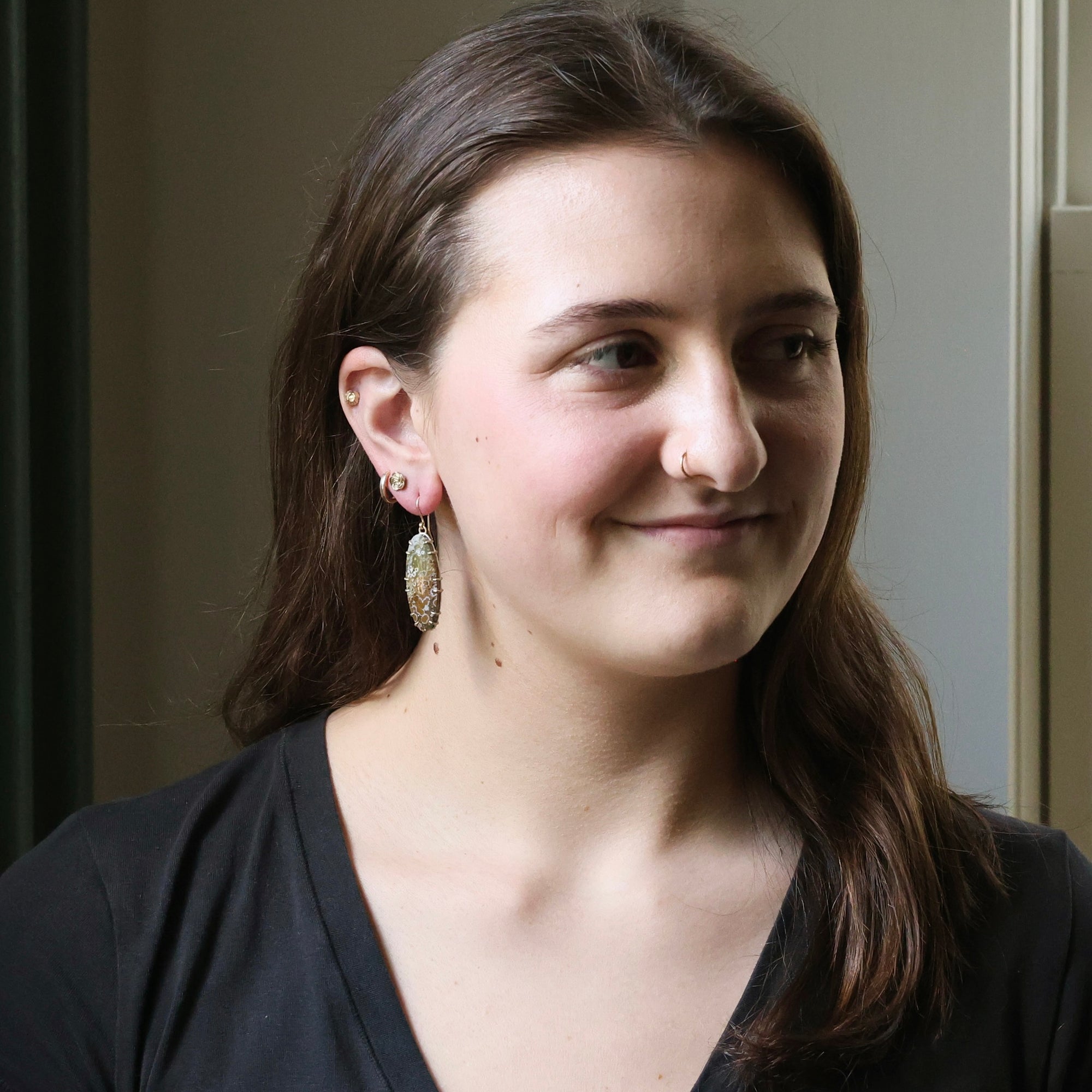 Woman wearing large earrings with a neutral background