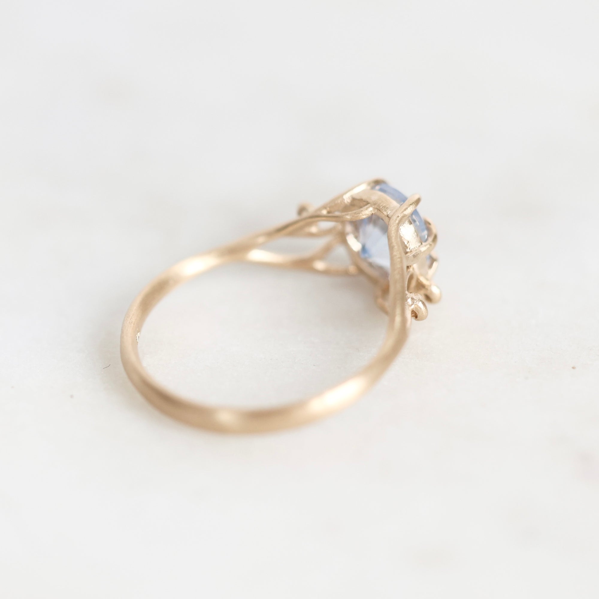 A gold ring with a small light blue gemstone, photographed on a plain white background.