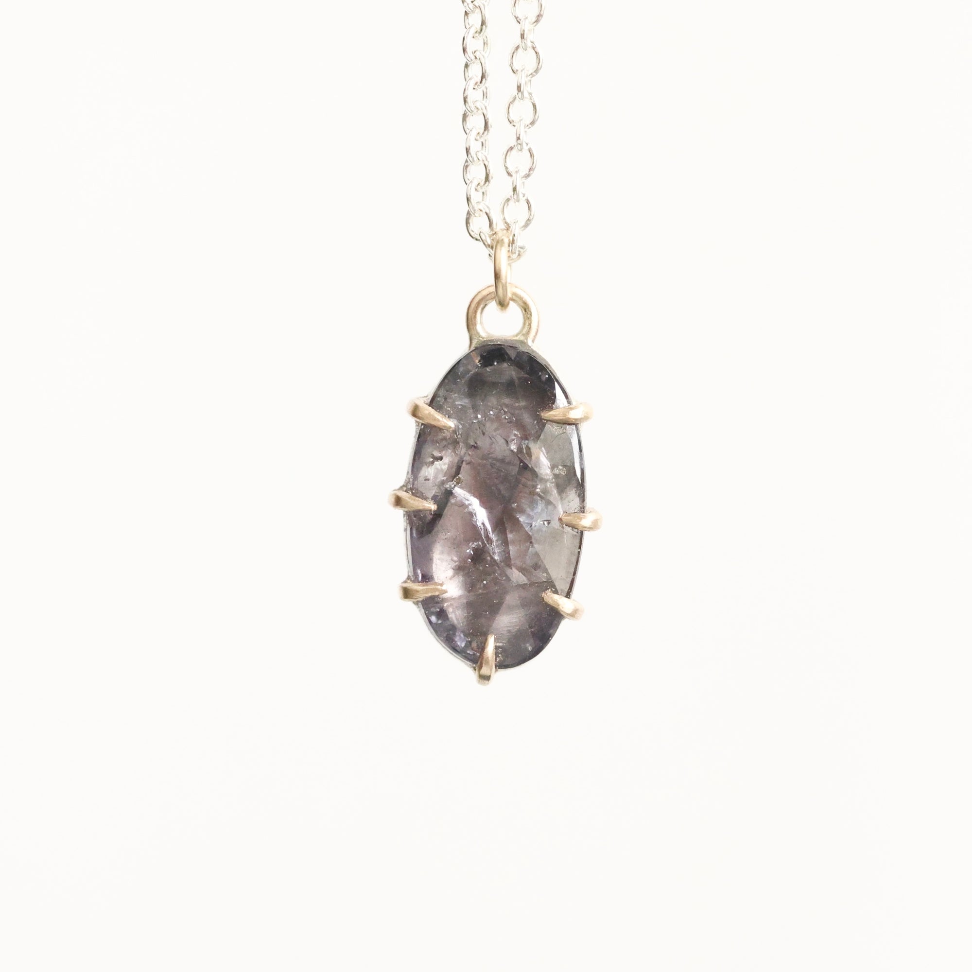 Necklace with a pendant featuring a gray stone and gold accents on a white background
