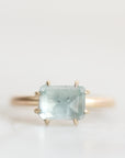 A gold ring featuring a rectangular light blue gemstone in a prong setting, photographed against a clean white background.