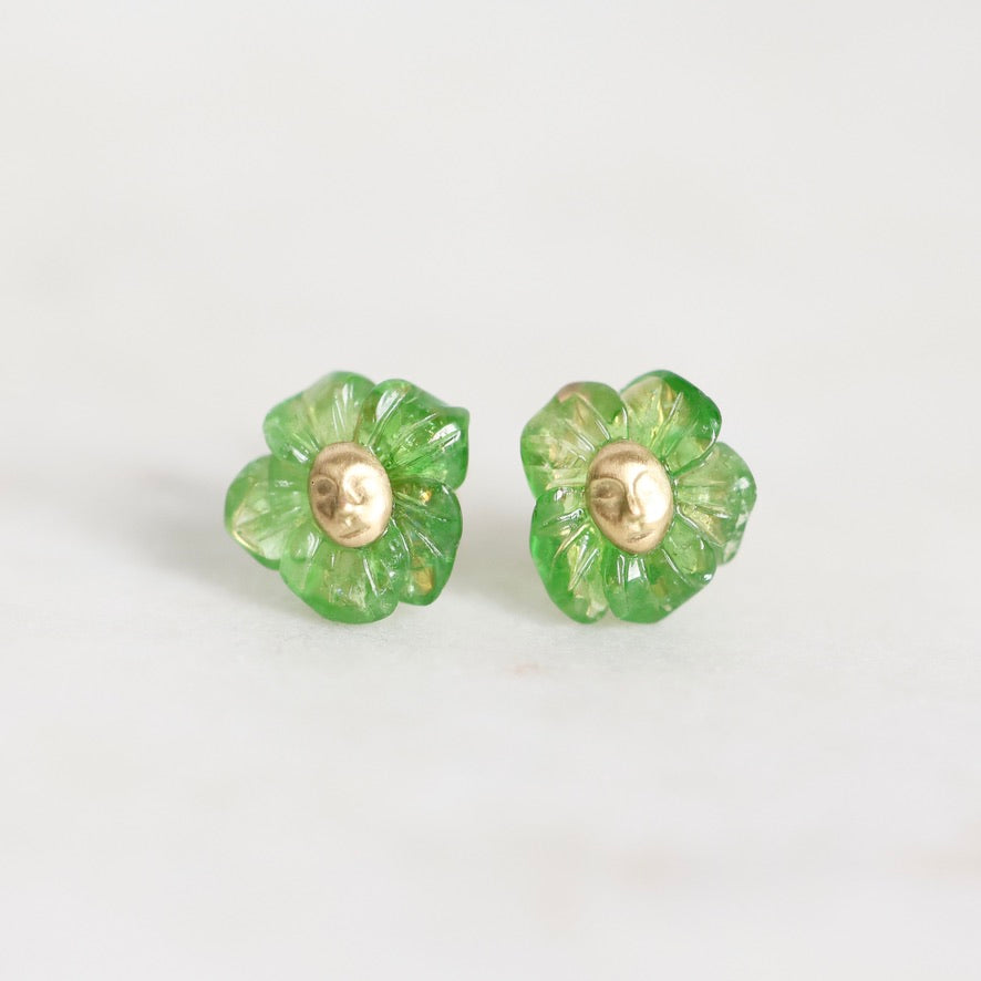 A pair of green flower-shaped stud earrings with a gold-tone center, shown on a plain light gray background.