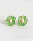 A pair of green flower-shaped stud earrings with a gold-tone center, shown on a plain light gray background.