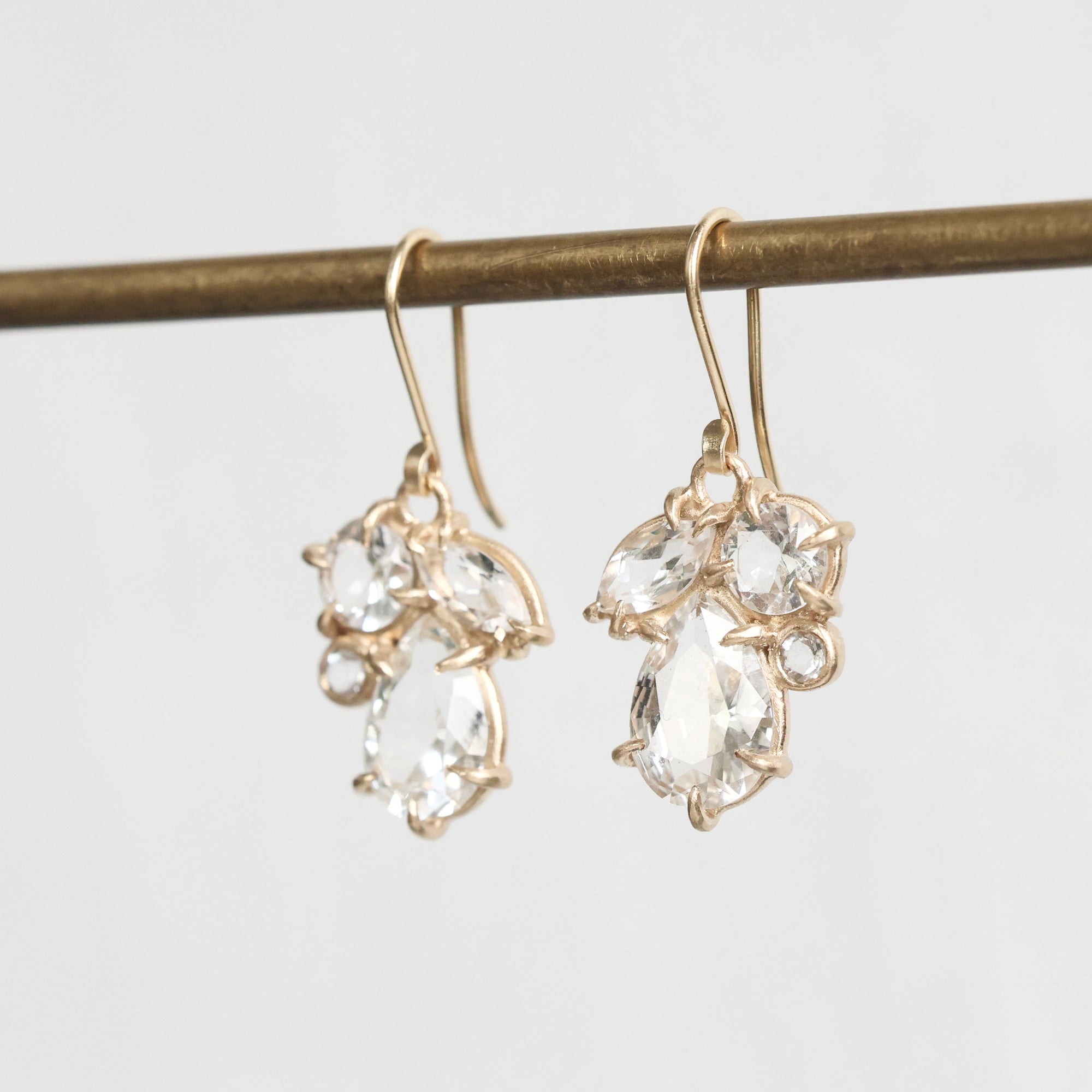 Gold earrings with clear gemstones on a light gray background