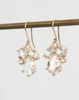 Gold earrings with clear gemstones on a light gray background