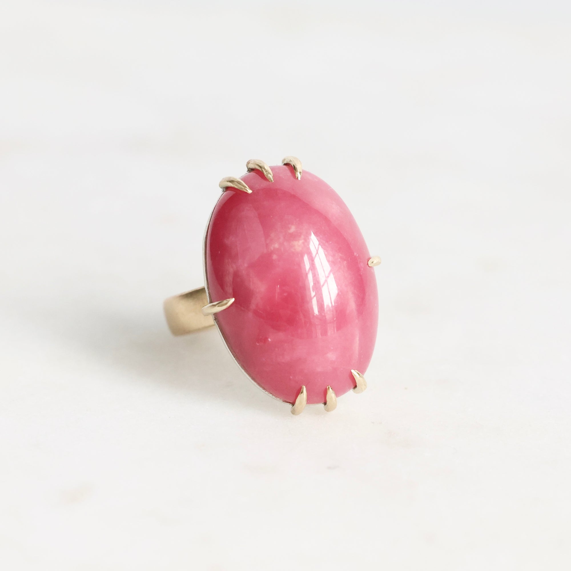 Ring with a pink stone and gold accents on a white background