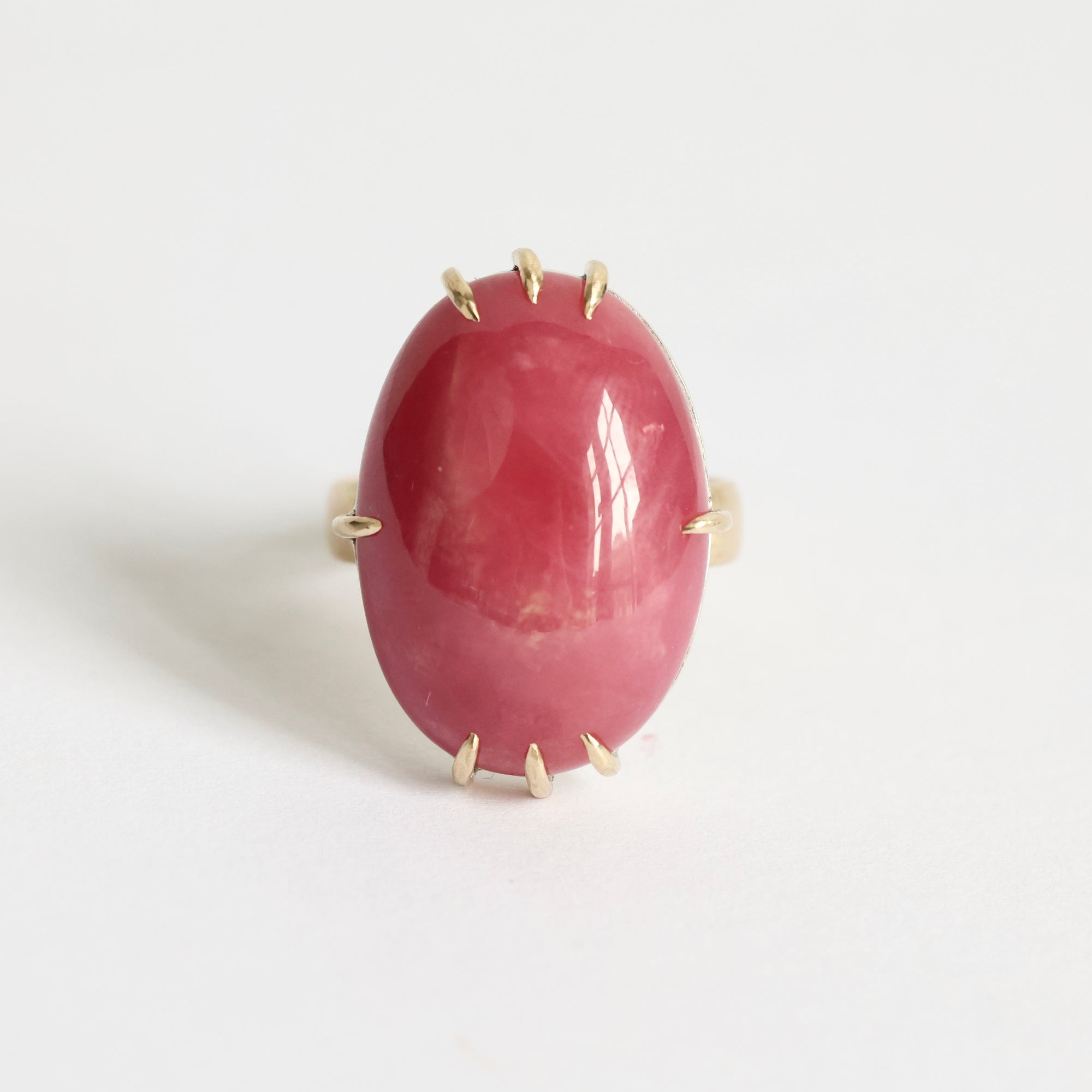 Ring with a large pink stone and gold accents on a white background