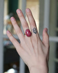Hand with a red ring and tattoo on a blurred indoor background