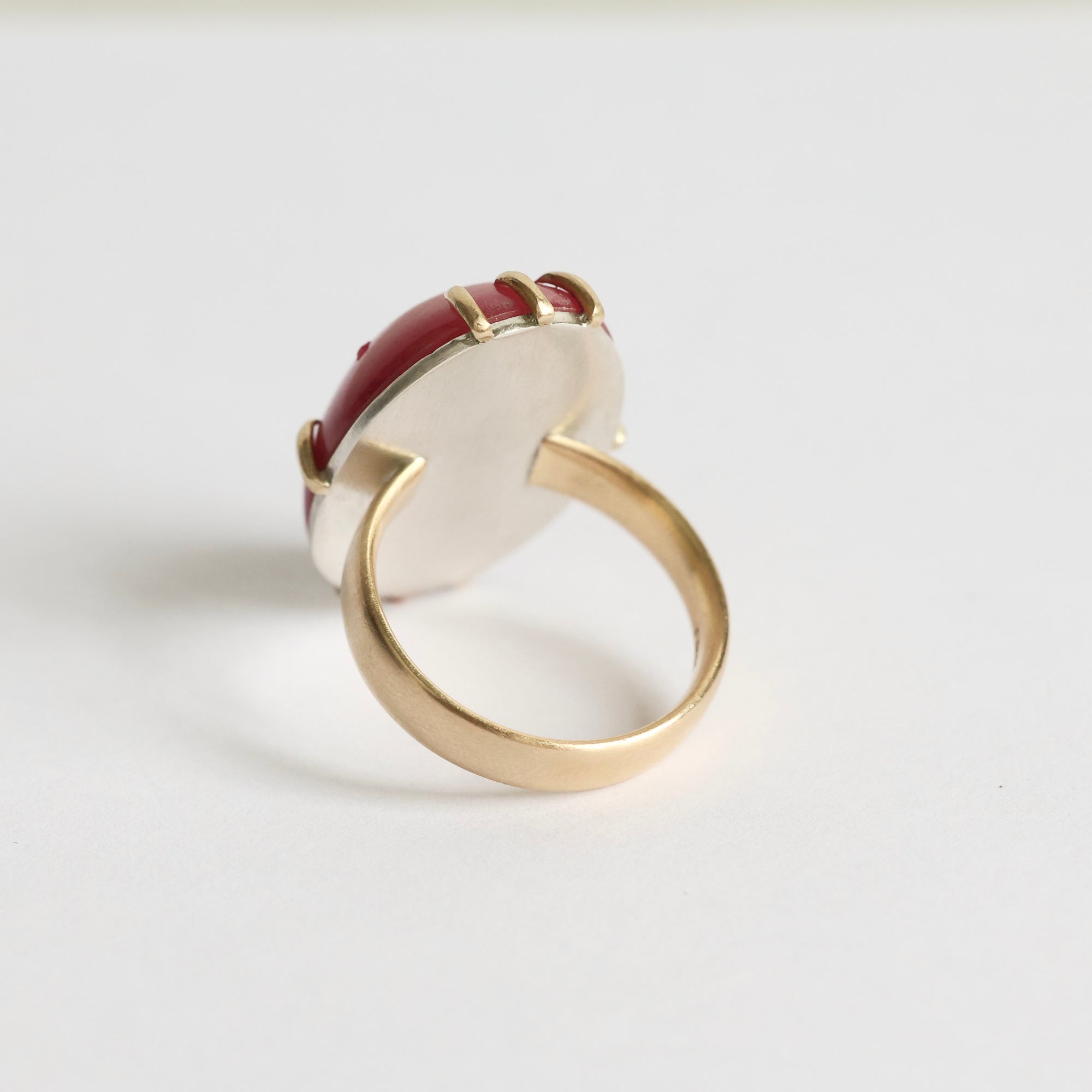 Gold ring with a red gemstone on a white background