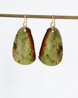 A pair of organic-shaped teardrop earrings made from natural green and brown jasper stone, hanging from gold fishhook wires against a plain white background.