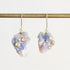 Fossilized opal drop earrings with gold barnacle details against a white background. 