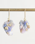 Fossilized opal drop earrings with gold barnacle details against a white background. 