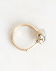 A gold ring with a small cluster of clear gemstones on the side, photographed on a plain white background.