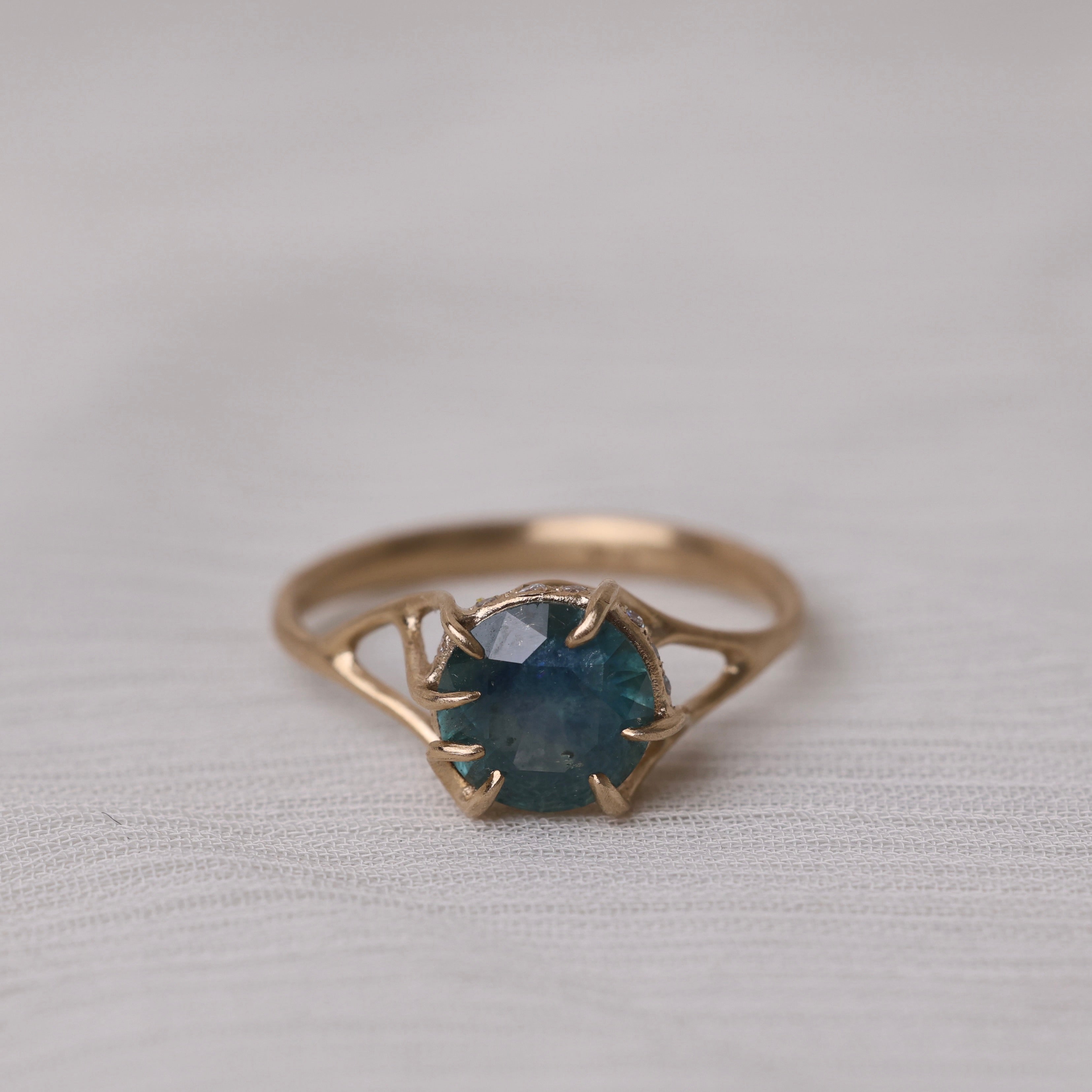 Gold ring with a green gemstone on a light gray background